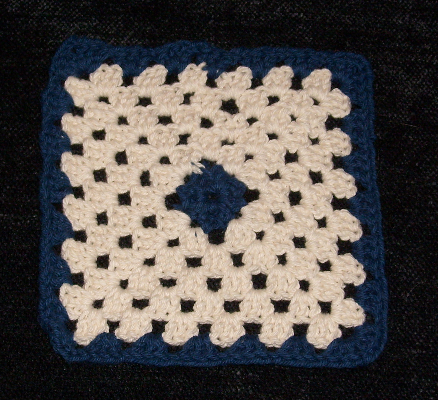 Cream crochet granny square with a blue centre and border.